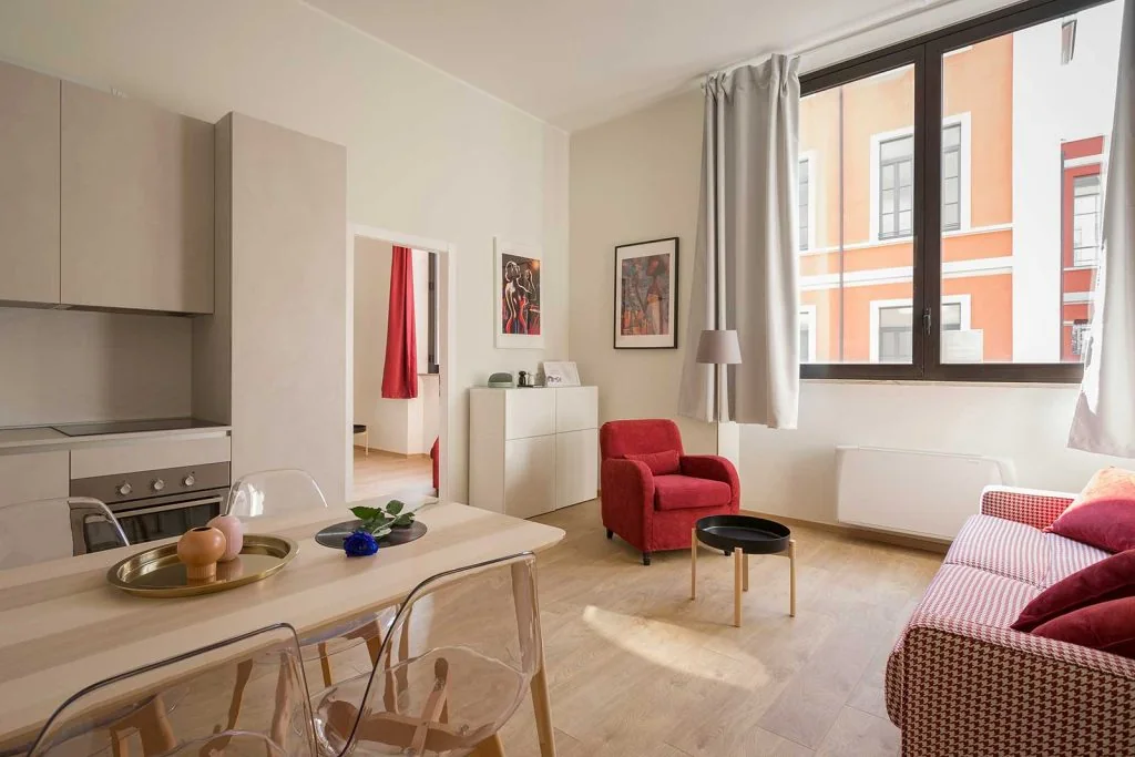 Apartment living and dining space with sofa, chairs, dining table and open kitchen