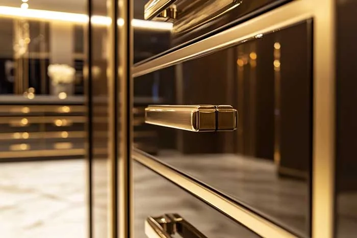 Close view of dark cabinetry fronts with gold-toned handles in a GEORGE Group furniture image
