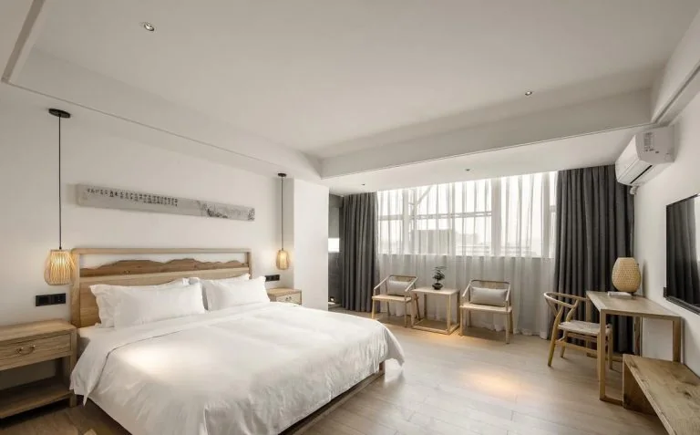 Hotel guest room with a bed, bedside tables, desk, chairs and a wall-mounted television