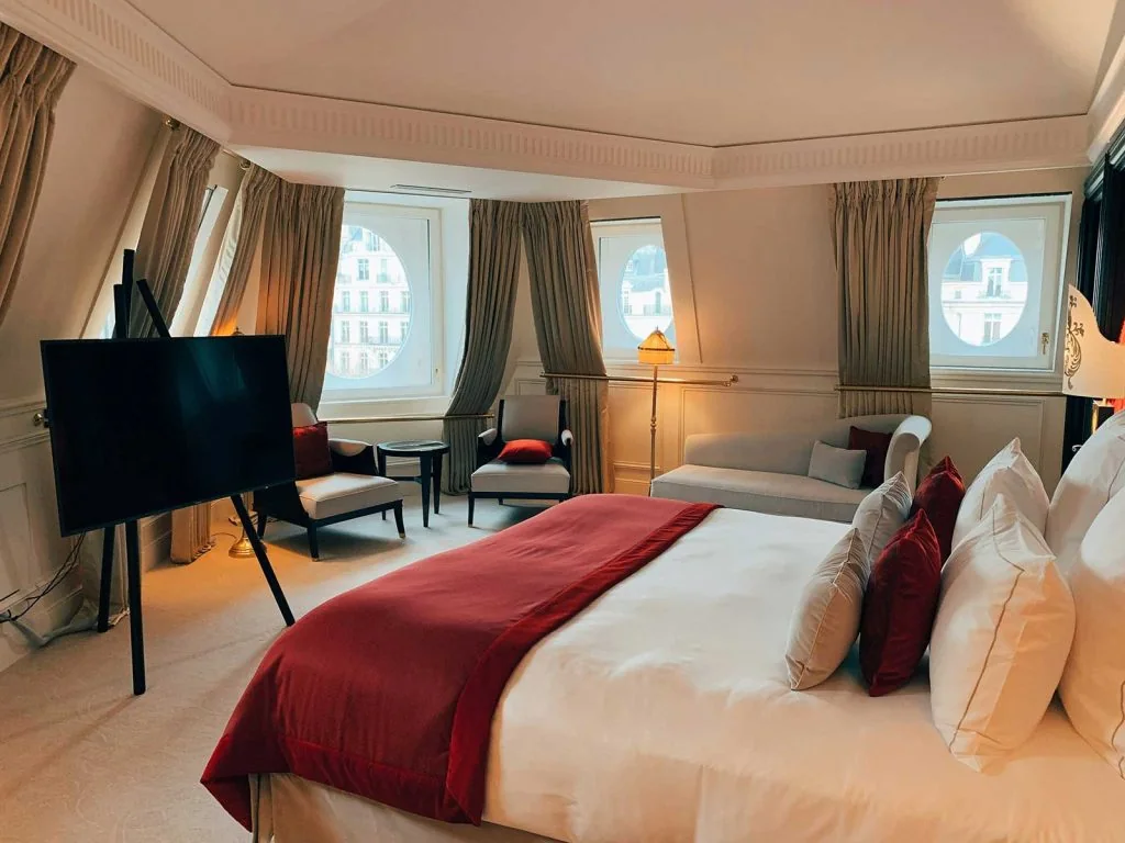 Hotel room with bed, bedside furniture, lounge chair and window wall