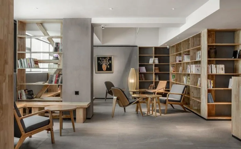 Lounge and reading area with armchairs, tables and full-height bookcases