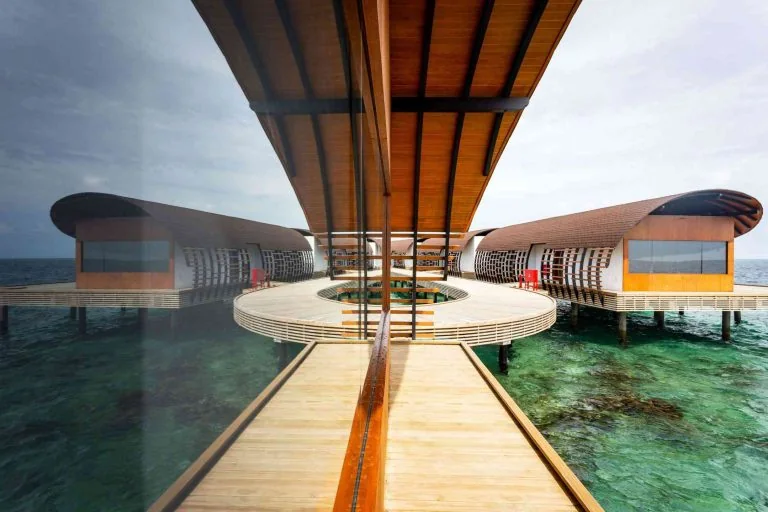 Covered overwater resort walkway with guest villas on both sides