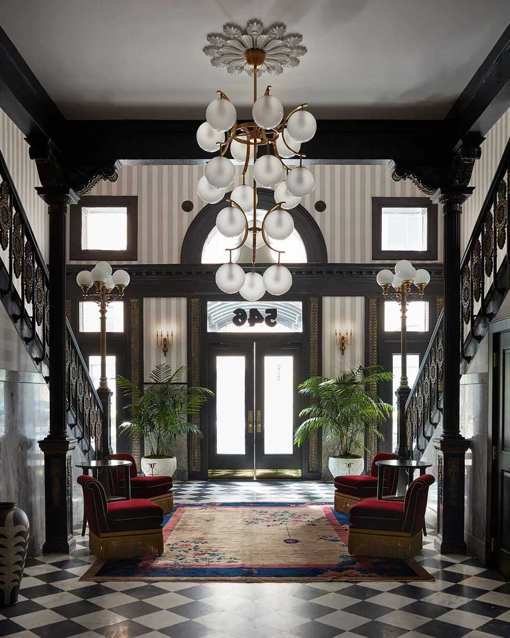 Boutique hotel entrance hall with patterned floor, chandelier and red seating