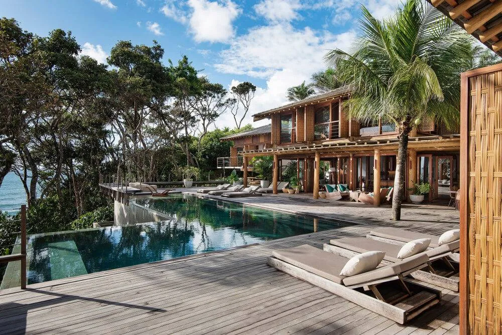Timber resort building and pool deck surrounded by tropical planting