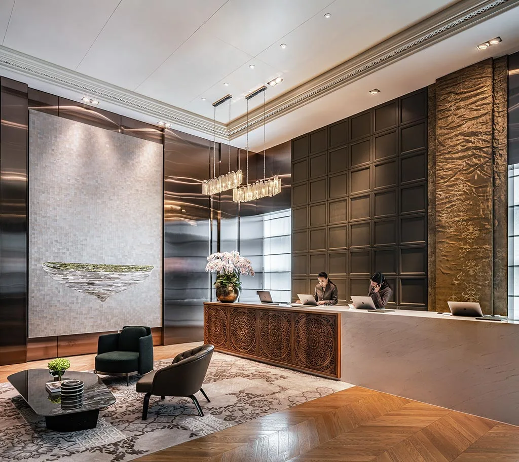 Reception lounge with armchairs, metal screens and a long desk