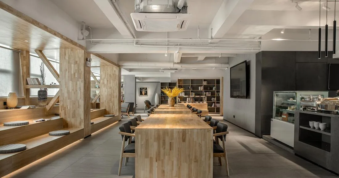 Hotel café or lounge with communal timber table, shelves and service counter