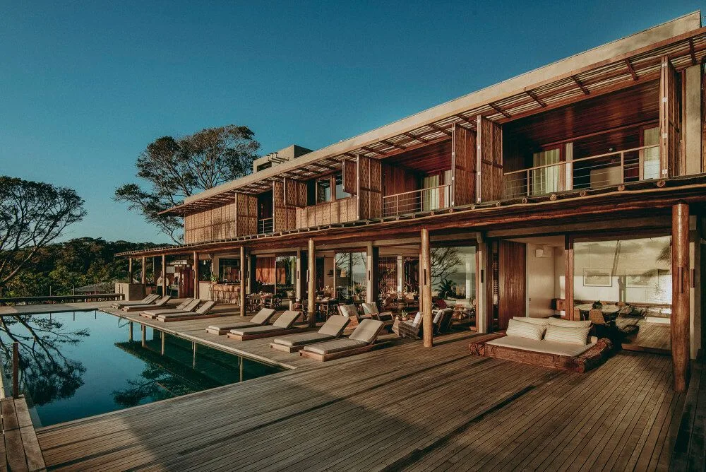 Long timber guest building beside a reflecting pool and shaded decks