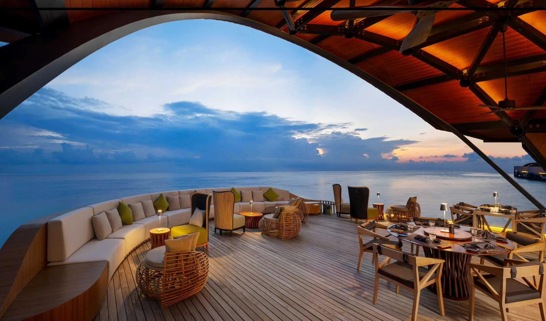 Covered oceanfront dining terrace with timber deck and mixed tables