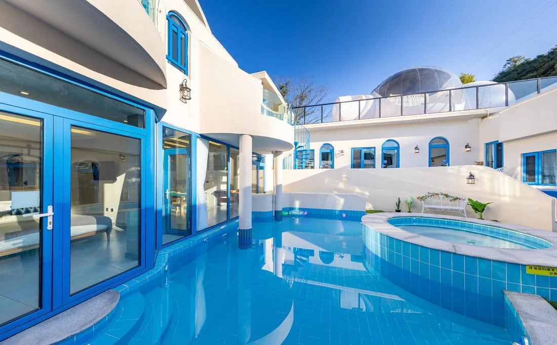 White-and-blue pool courtyard surrounded by guest-room doors and terraces