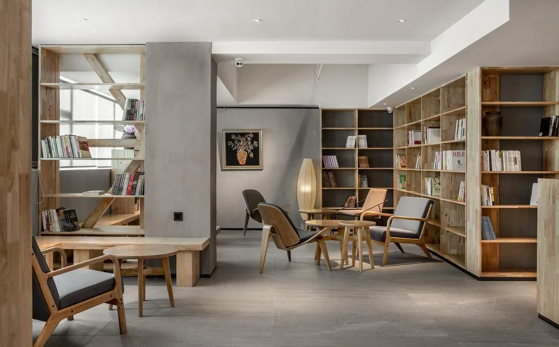 Library-style lounge with chairs, tables and full-height shelving