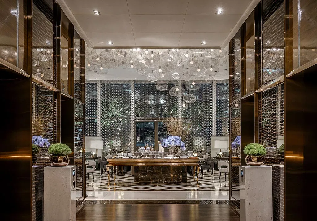 Public seating area with tables, armchairs, floral arrangements and decorative screens