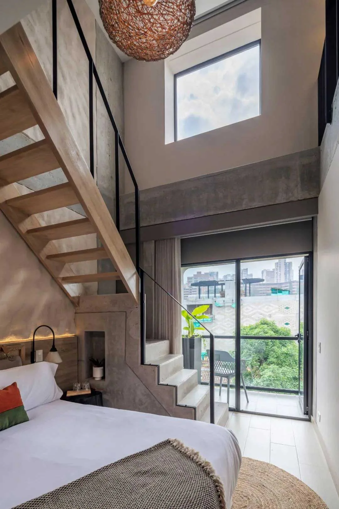 Duplex guest room with a bed, timber stair, high window and balcony