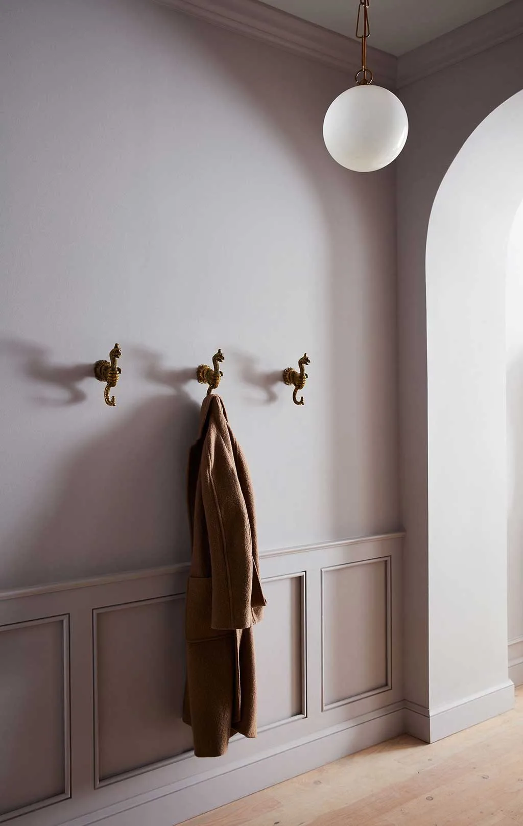 Arched interior niche with hooks, wall panelling and a pendant light