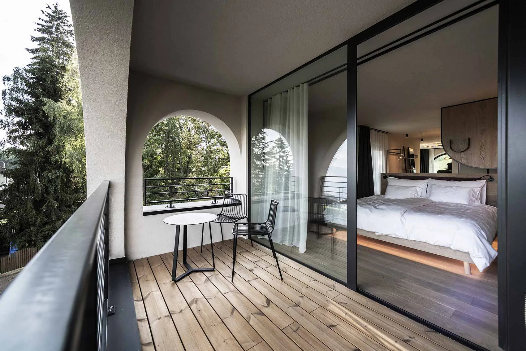 Covered guest-room balcony with a small table, chairs and arched opening