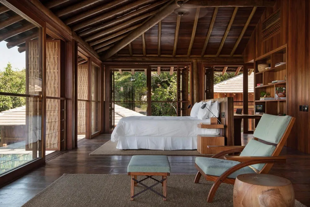 Open timber guest pavilion with bed, bench and screened walls