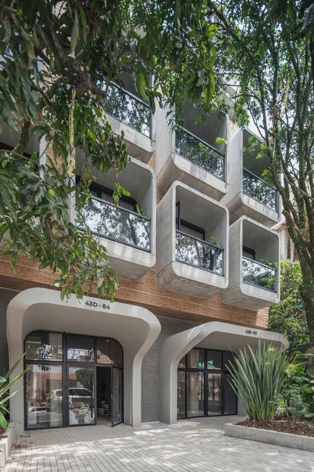 Hotel facade viewed through mature trees at the street edge