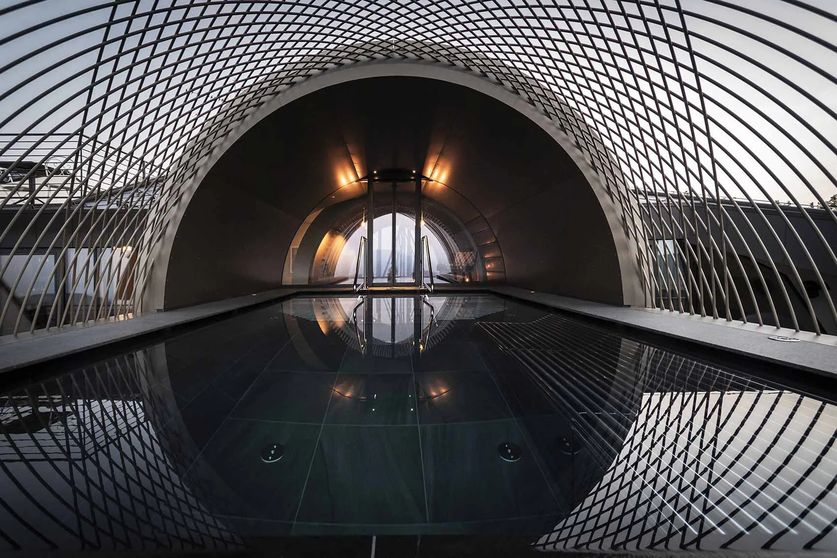 Indoor pool beneath a dark arched ceiling and patterned screen