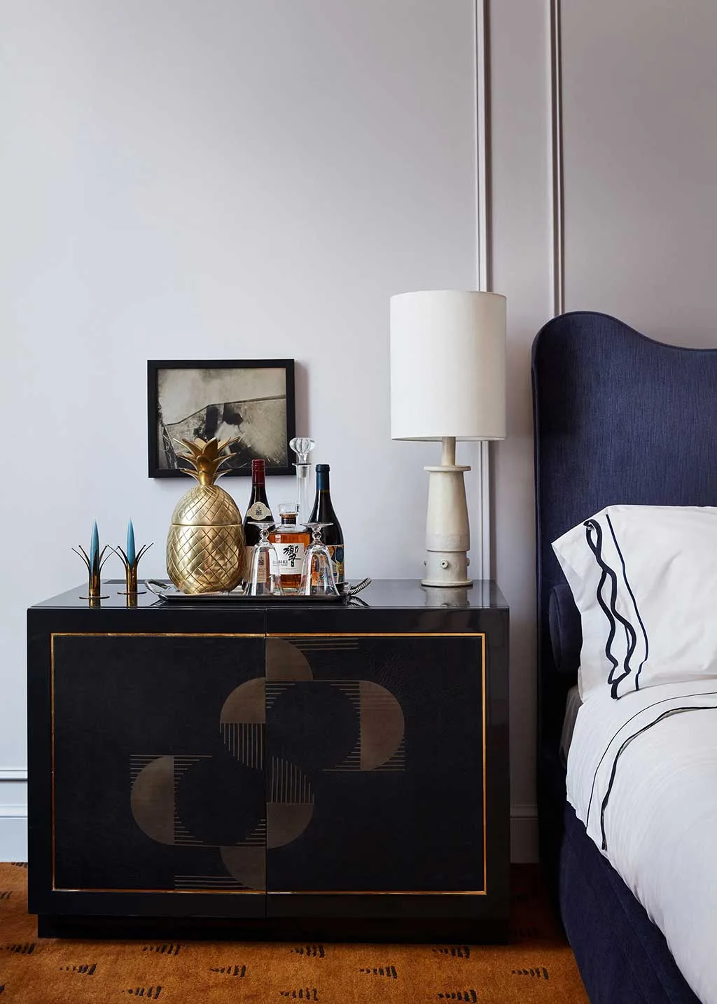 Guest-room bedside cabinet with lamp and upholstered headboard
