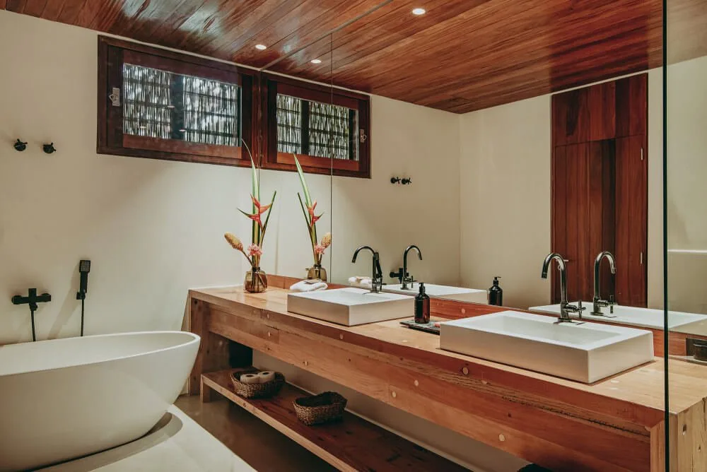 Guest bathroom with long timber vanity, twin basins and screened window