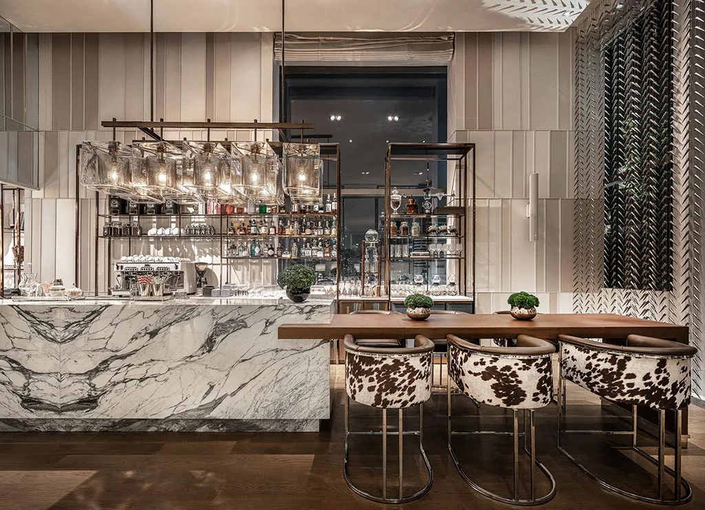 Marble-fronted bar with stools, bottle display and decorative lighting