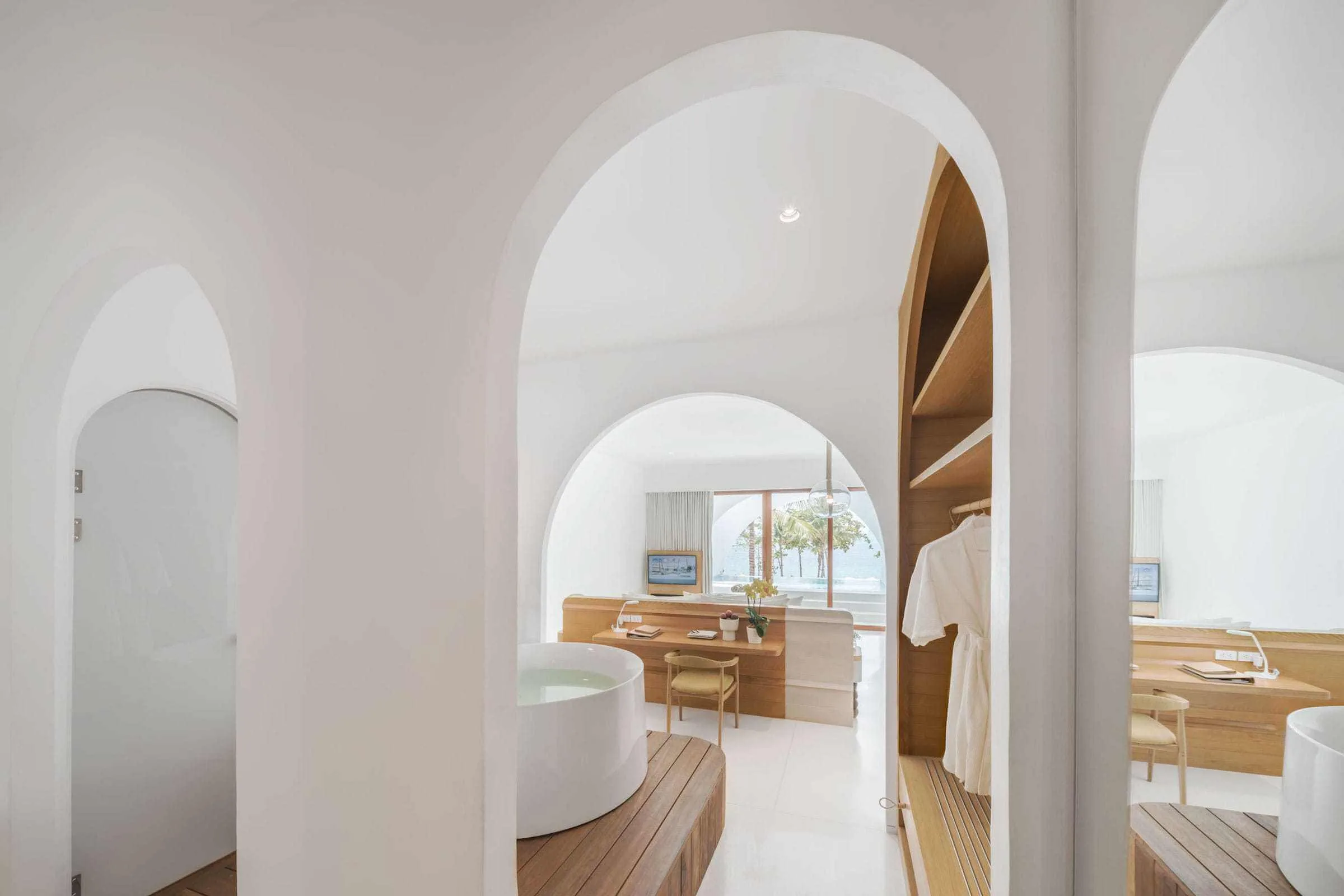 White arched passage linking bath, desk and sleeping areas