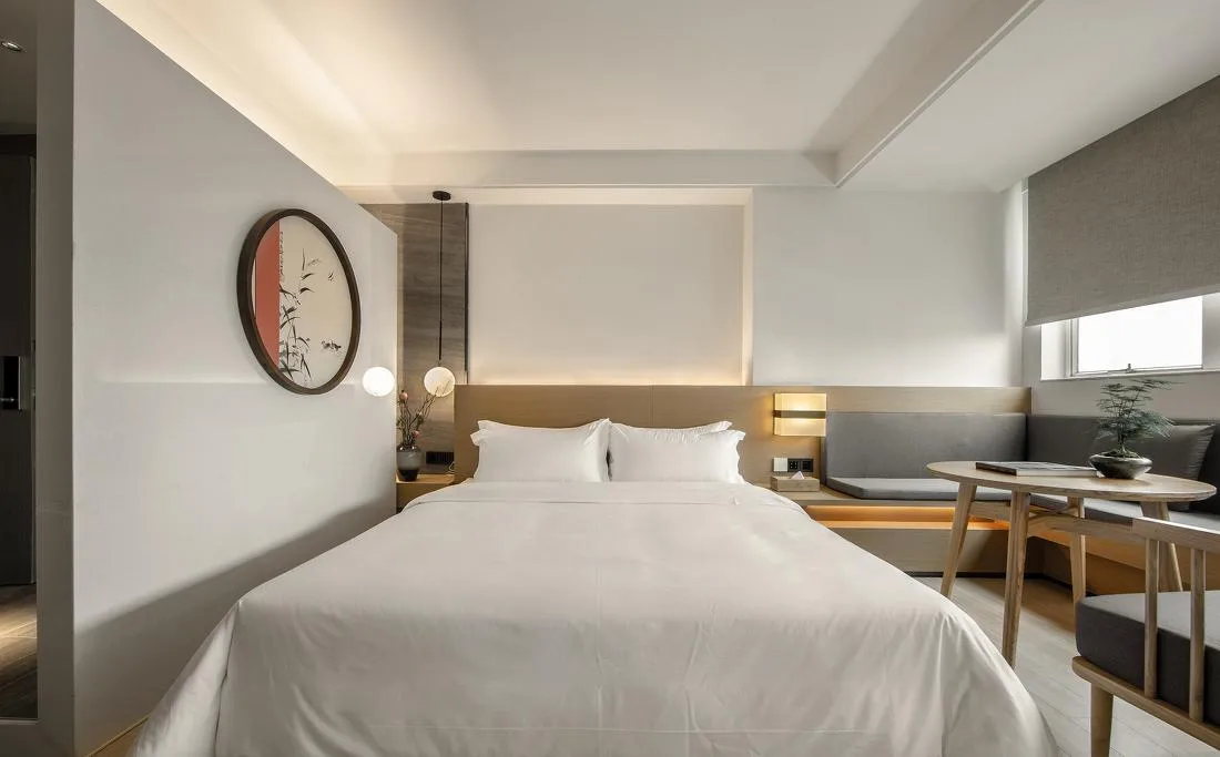 Guest room with bed, long desk and wall clock