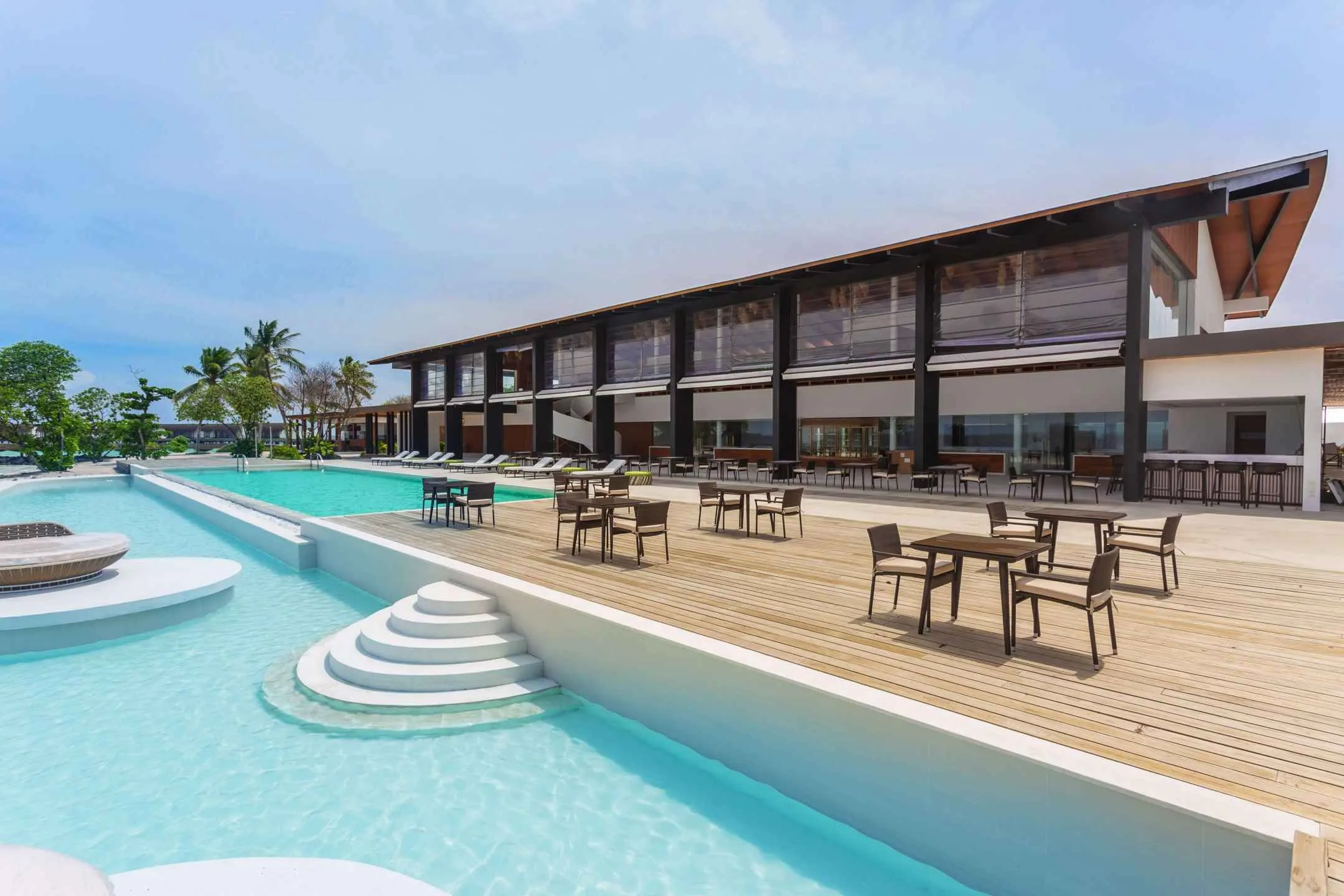 Pool terrace with tables beside a long, low public building
