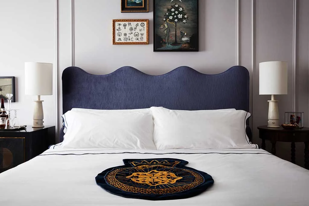 Guest bed with sculpted blue headboard, bedside tables and lamps