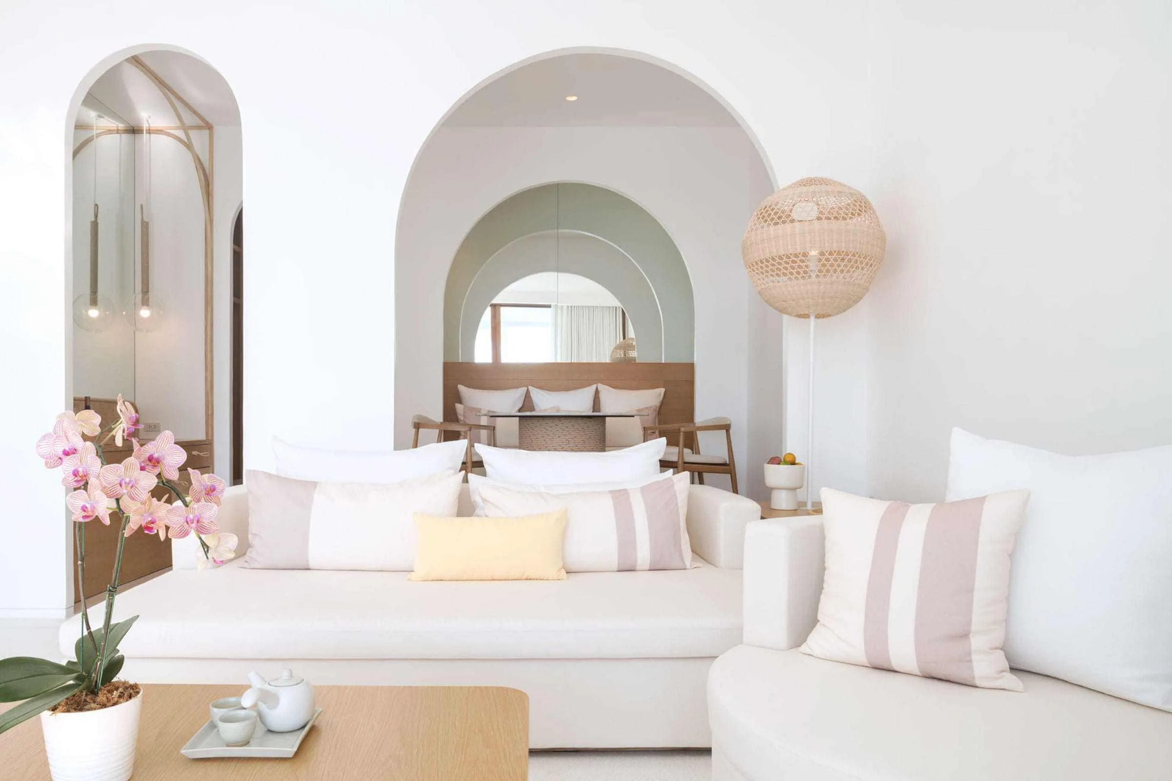 White guest-room sitting and sleeping area with curved openings and pale upholstery