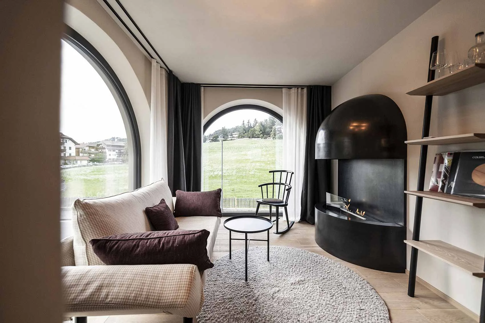 Suite sitting area with sofa, chairs, shelving and a curved fireplace