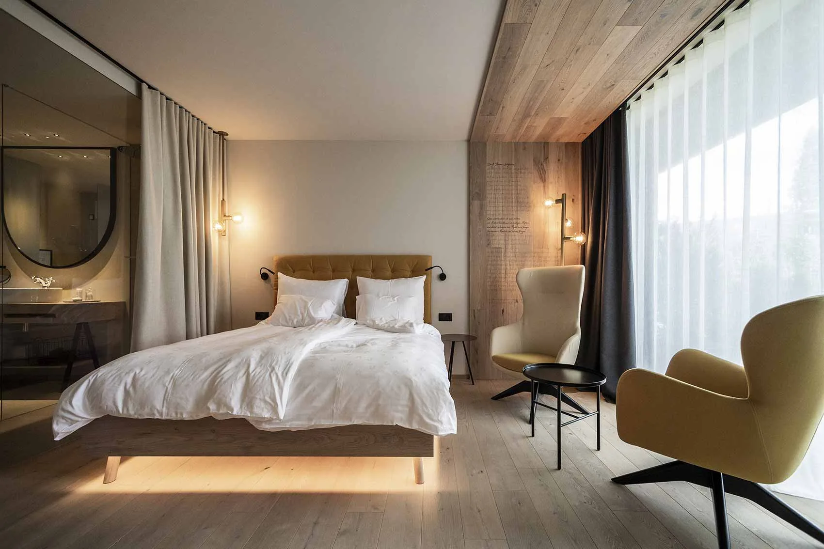 Guest bedroom with timber bed, lounge chair and full-height window