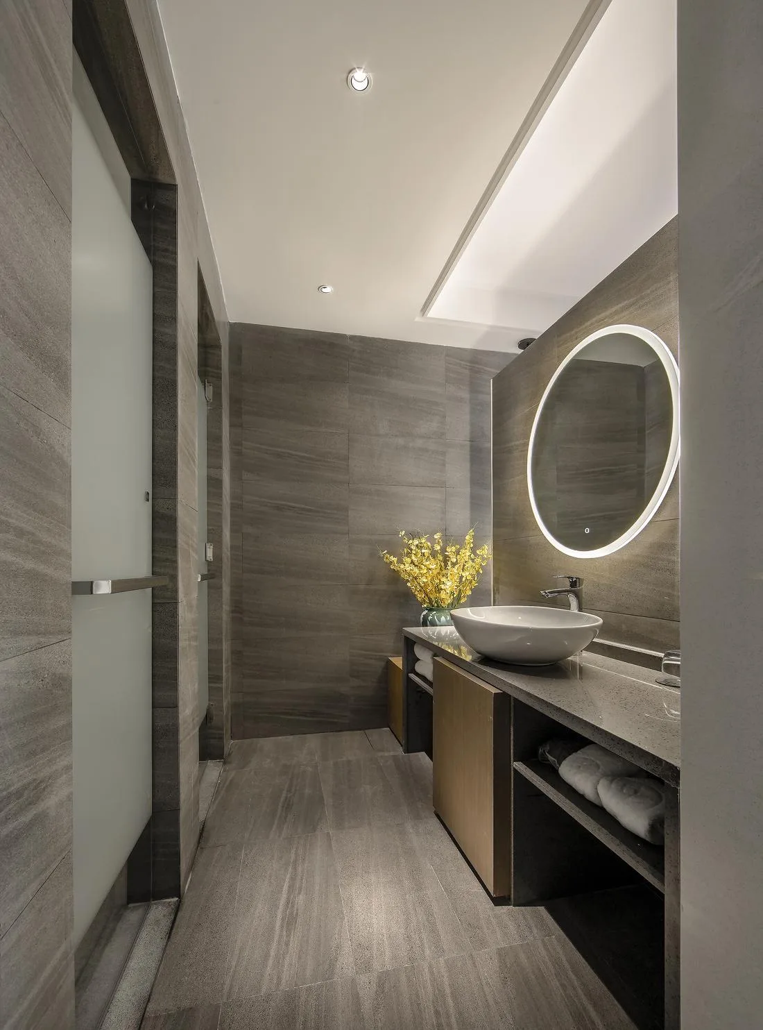Guest bathroom vanity with round illuminated mirror and open shelving