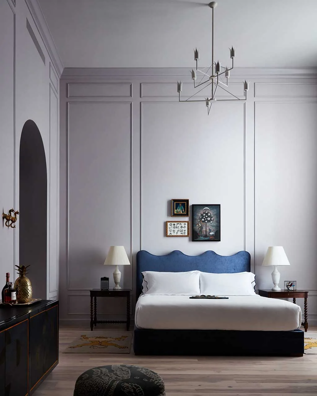 Guest bedroom with bed, wall art, simple chandelier and panelled walls
