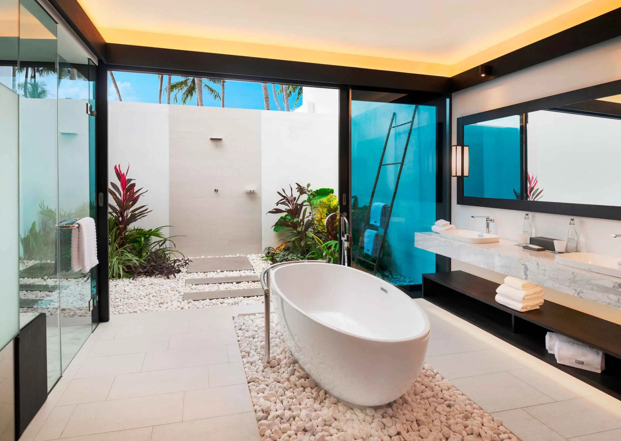Bright guest bathroom with freestanding bath, twin vanity and planted courtyard