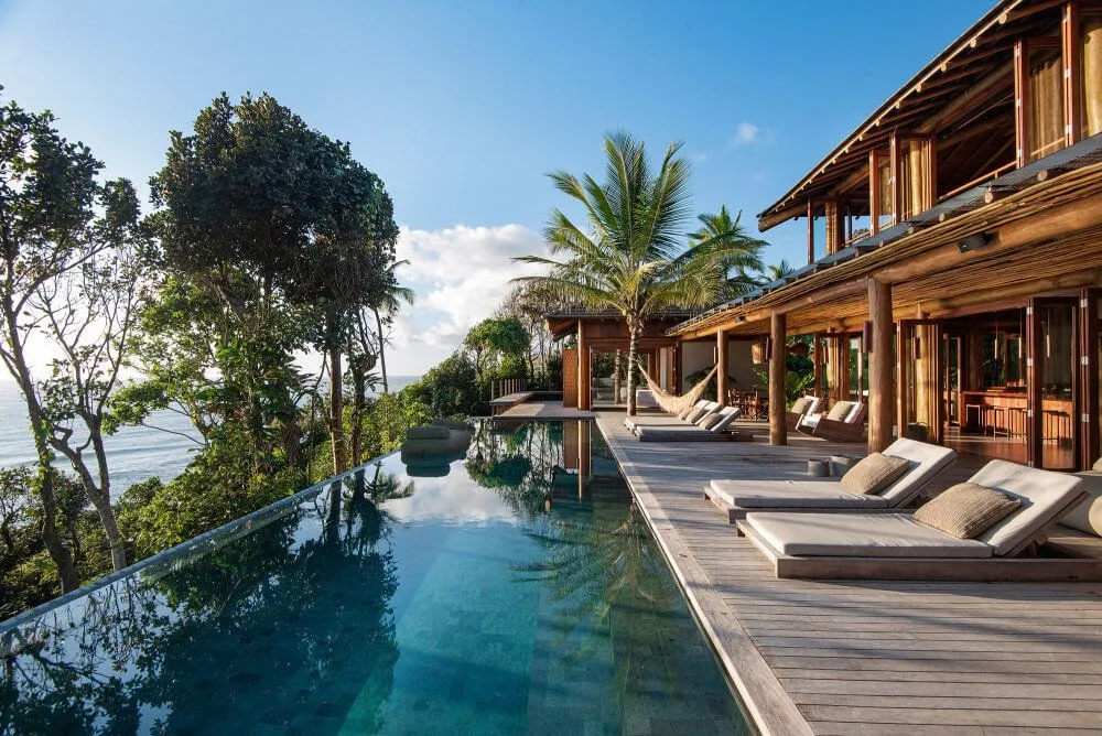 Resort pool and timber guest building framed by trees