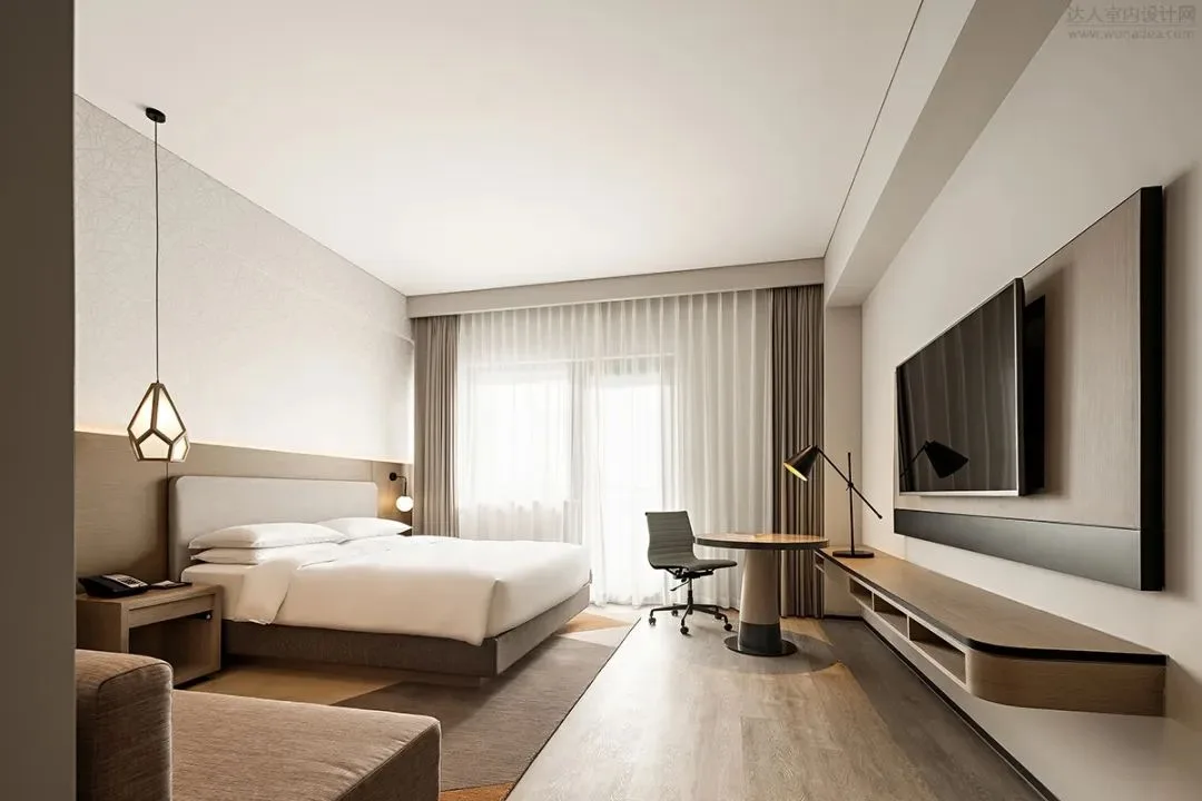 Guest room with bed, desk chair, television and open floor area