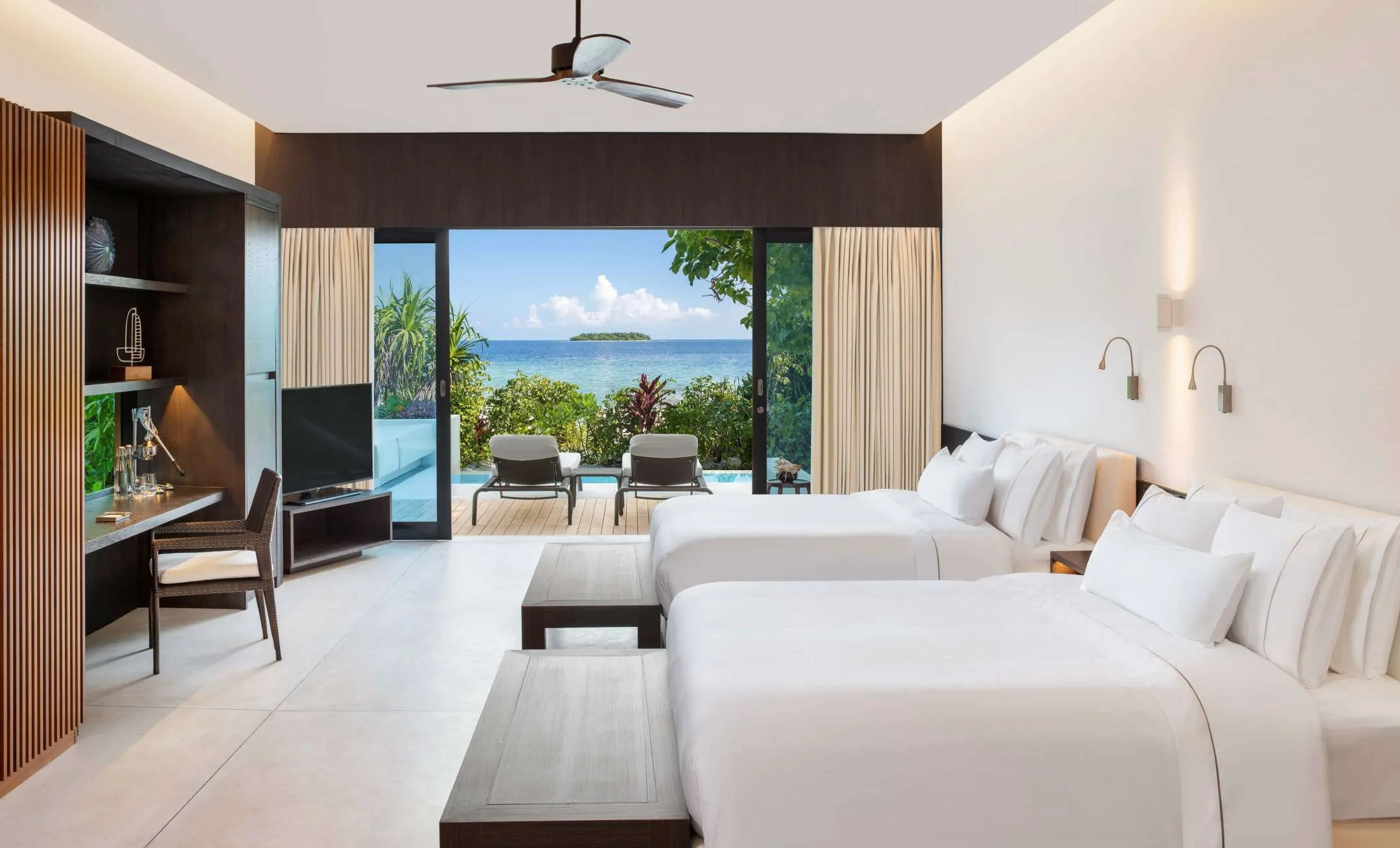 Oceanfront twin guest room with desks, shelving and sliding doors to the view