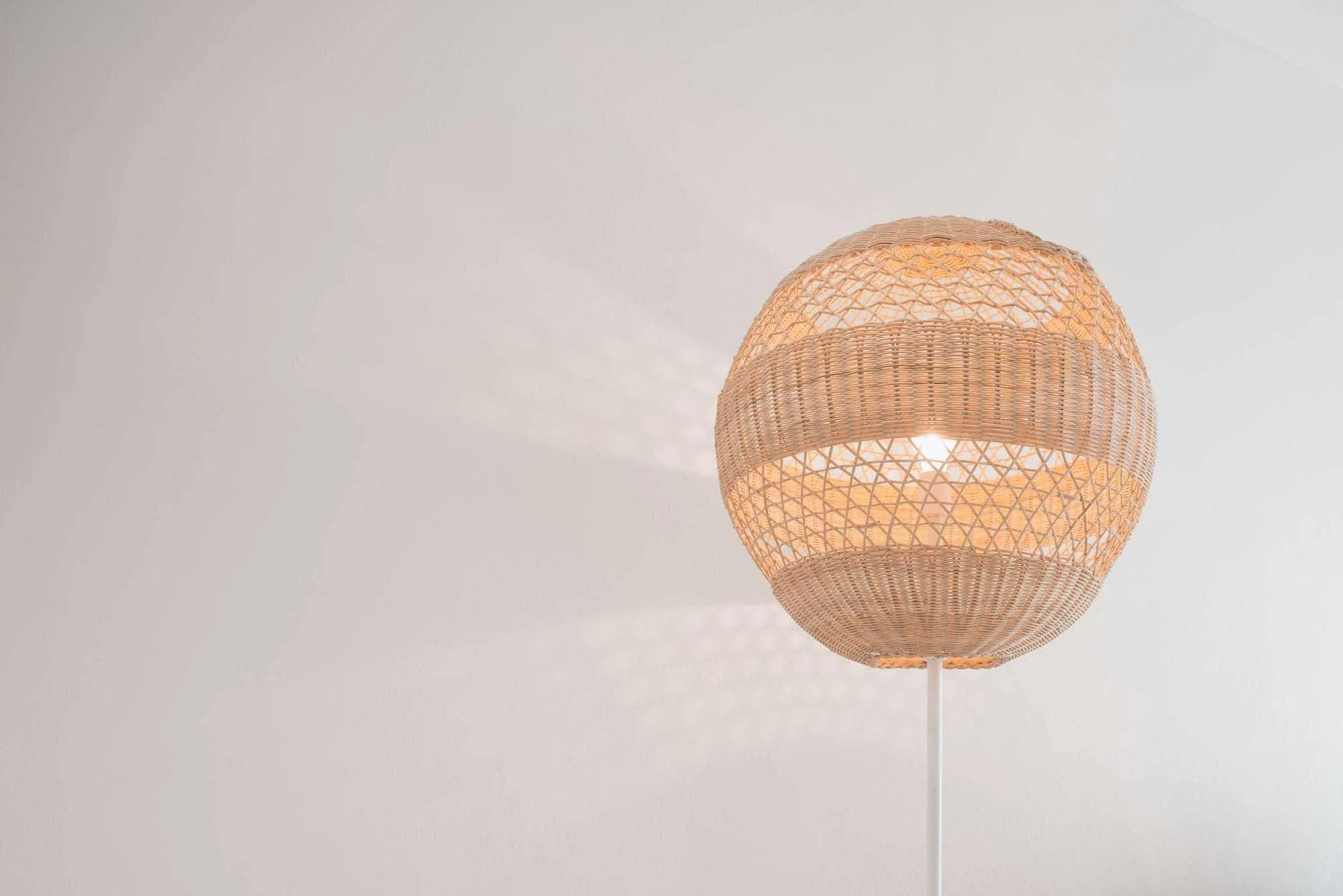 Woven pendant light against a white guest-room ceiling