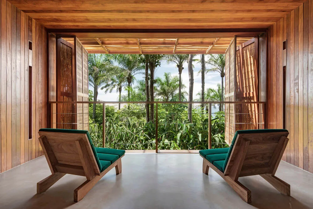 Window-bay seating with two timber chairs facing tropical planting