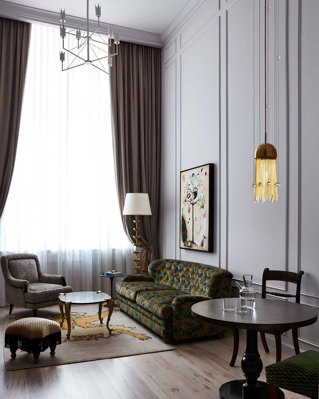 Guest-room sitting area with green sofa, armchair, table and tall window