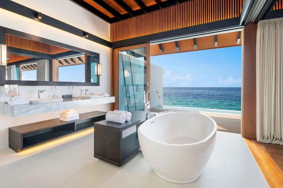 Oceanfront resort bathroom with timber details, twin basins, mirrors and a freestanding bath facing the sea