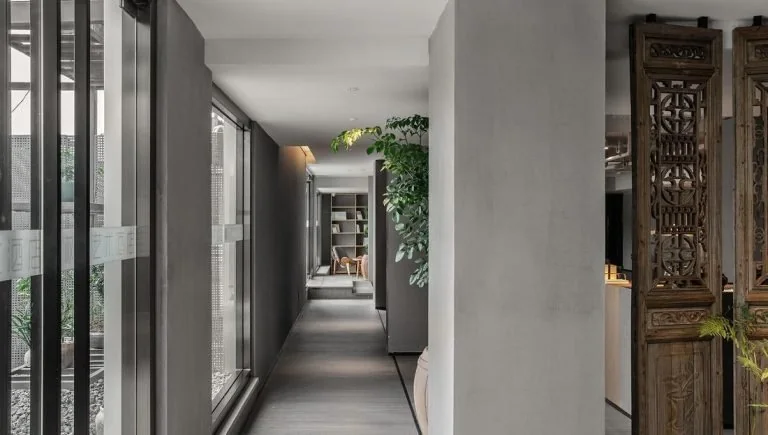 Hotel corridor with room doors, a window at the end and decorative wall panels