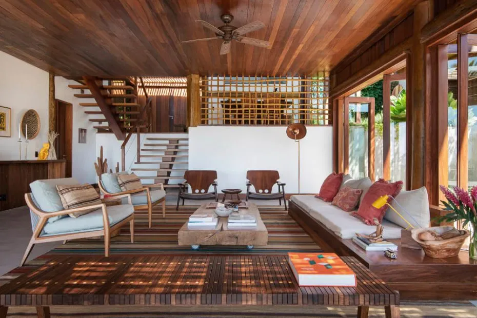 Timber beach-resort lounge with mixed seating, woven screens, exposed roof structure and tropical planting outside