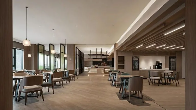 Long hotel dining area with repeated tables, chairs, counters and pendant lights