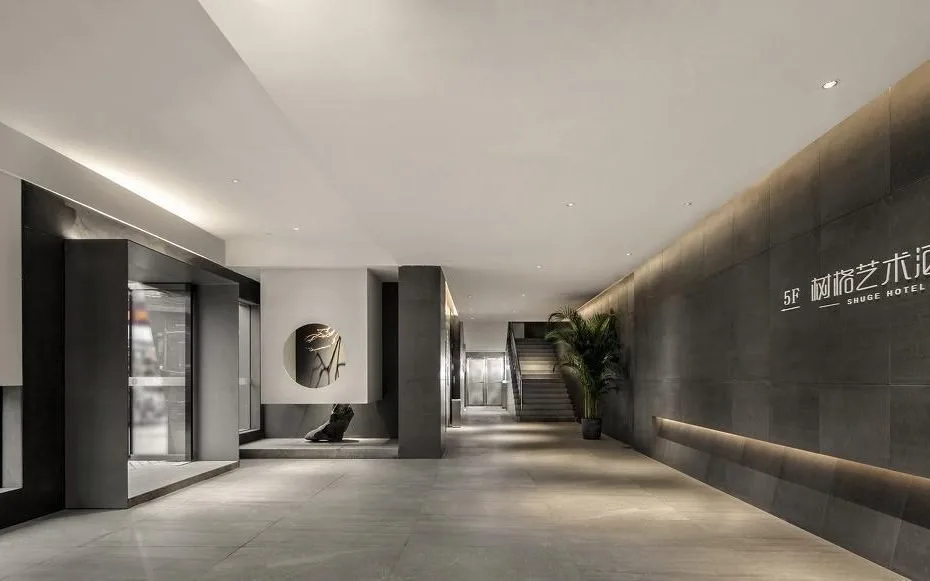 Modern Shuge Hotel lift lobby with concrete-toned walls, dark lift doors and restrained lighting